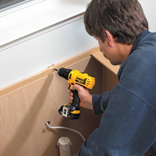 Three eighths of an inch Drill driver is being used by a person to drill  worksurface.