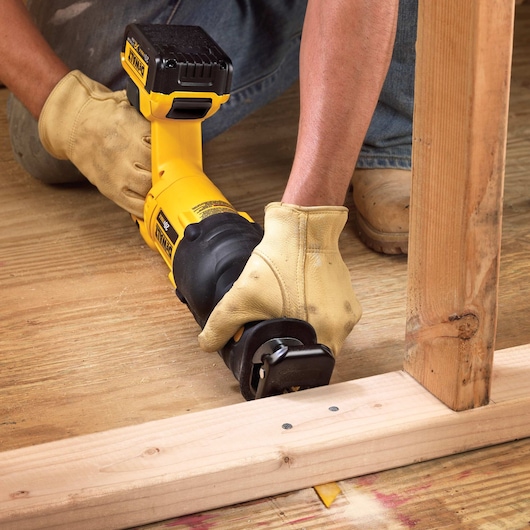 Cordless Reciprocating Saw being used on narrow space under wooden frame.